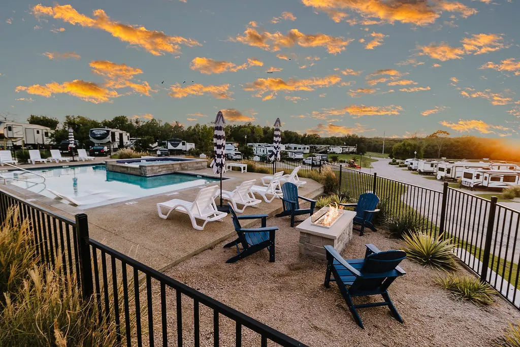 Pool deck, spa, and fire-pit patio at dusk — a warm welcome for travelers exploring Sugar Hill and nearby North Texas cities.